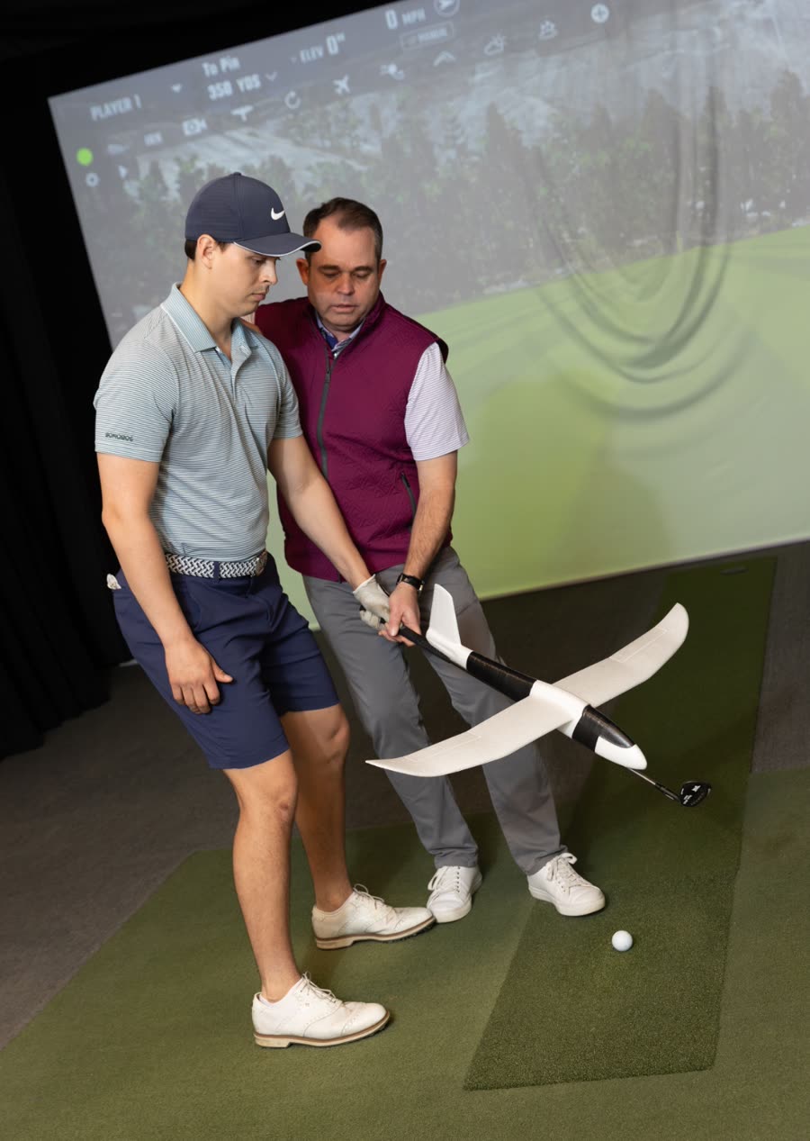 Rick Silva coaching a golfer with a training tool in the Movement 3 Golf studio